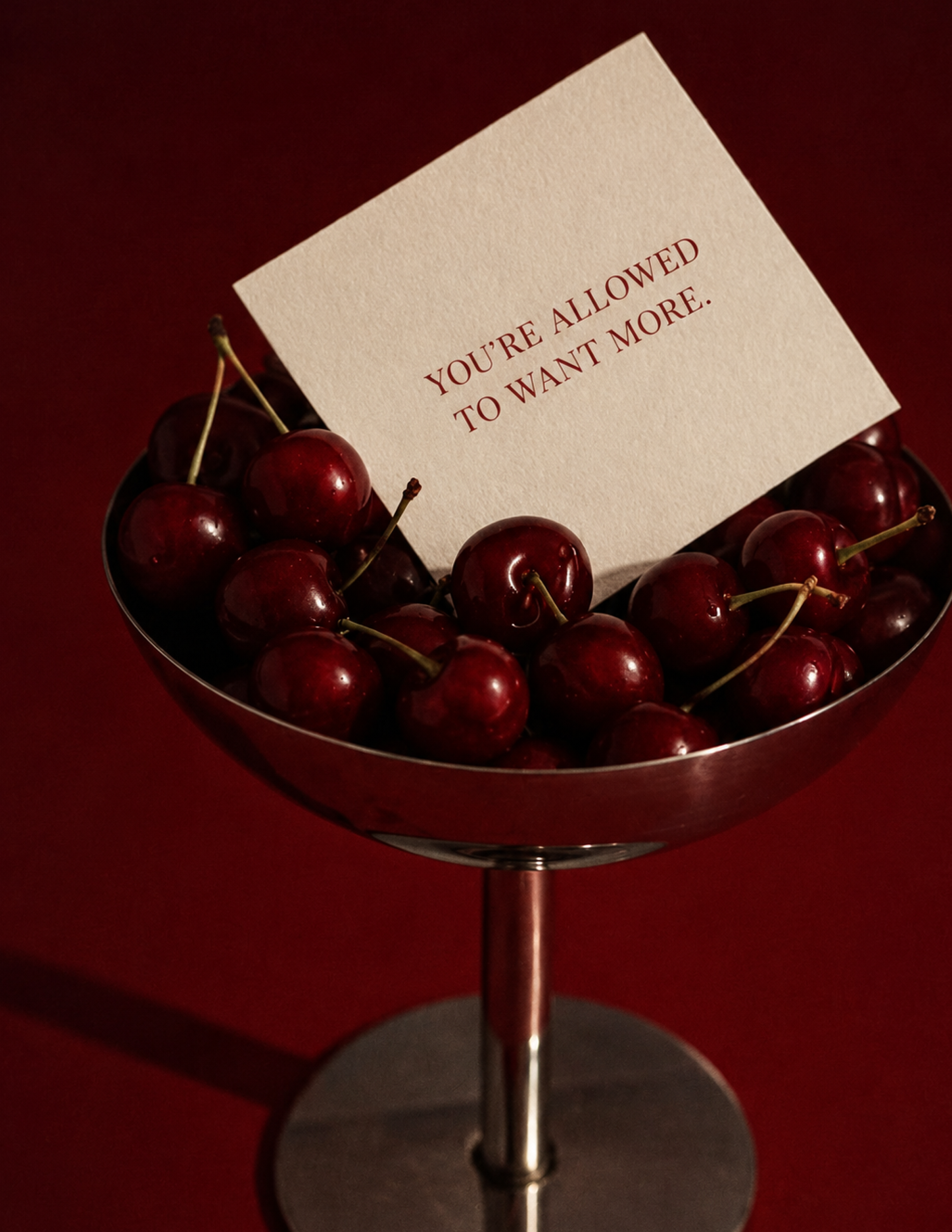 A bowl of cherries holding a card that says You’re allowed to want more