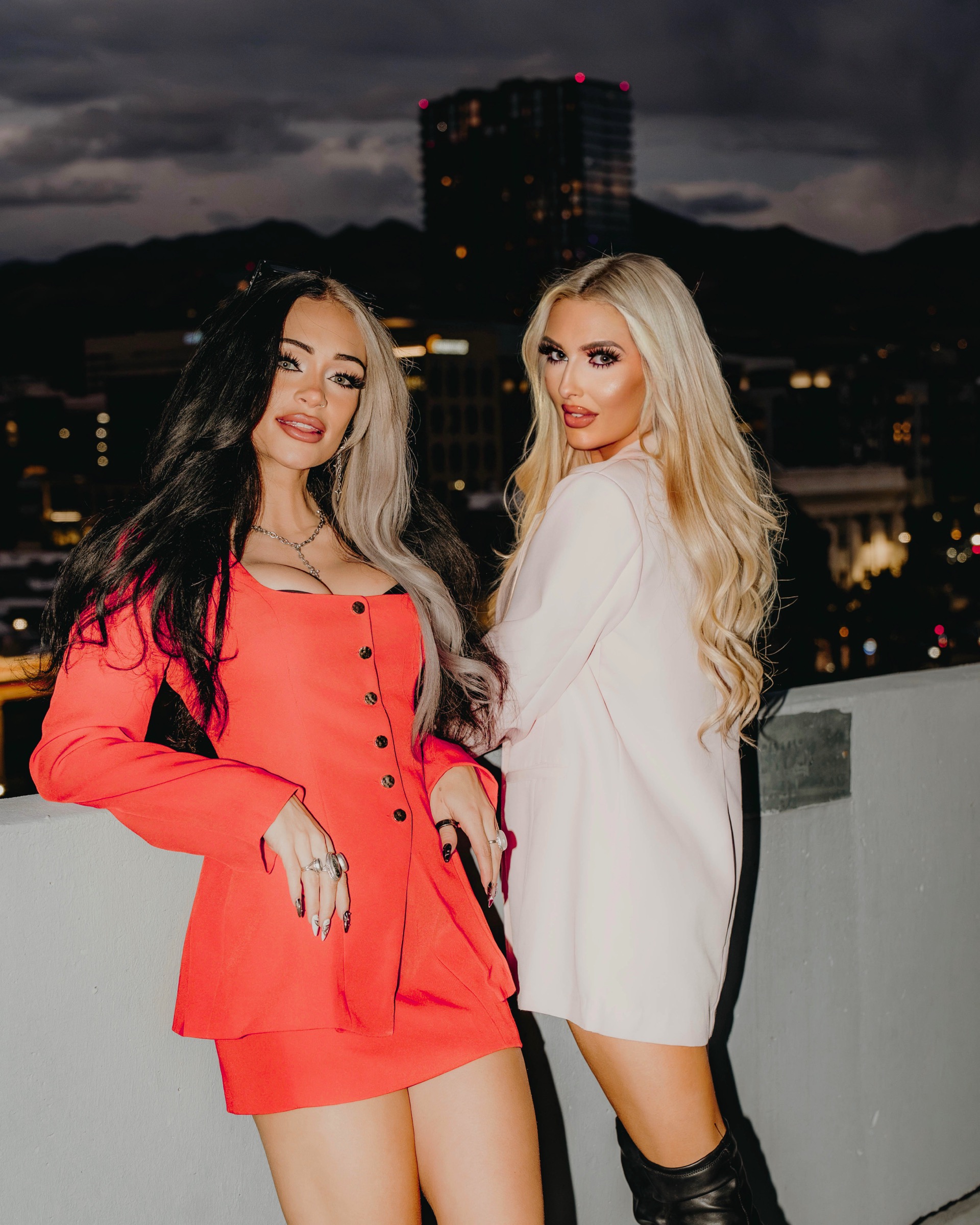 Blaire and Mae posing in pink and red against the night skyline